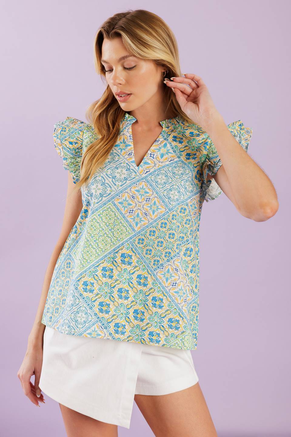 A printed woven top featuring ruffled neckline with V front and ruffled sleeve