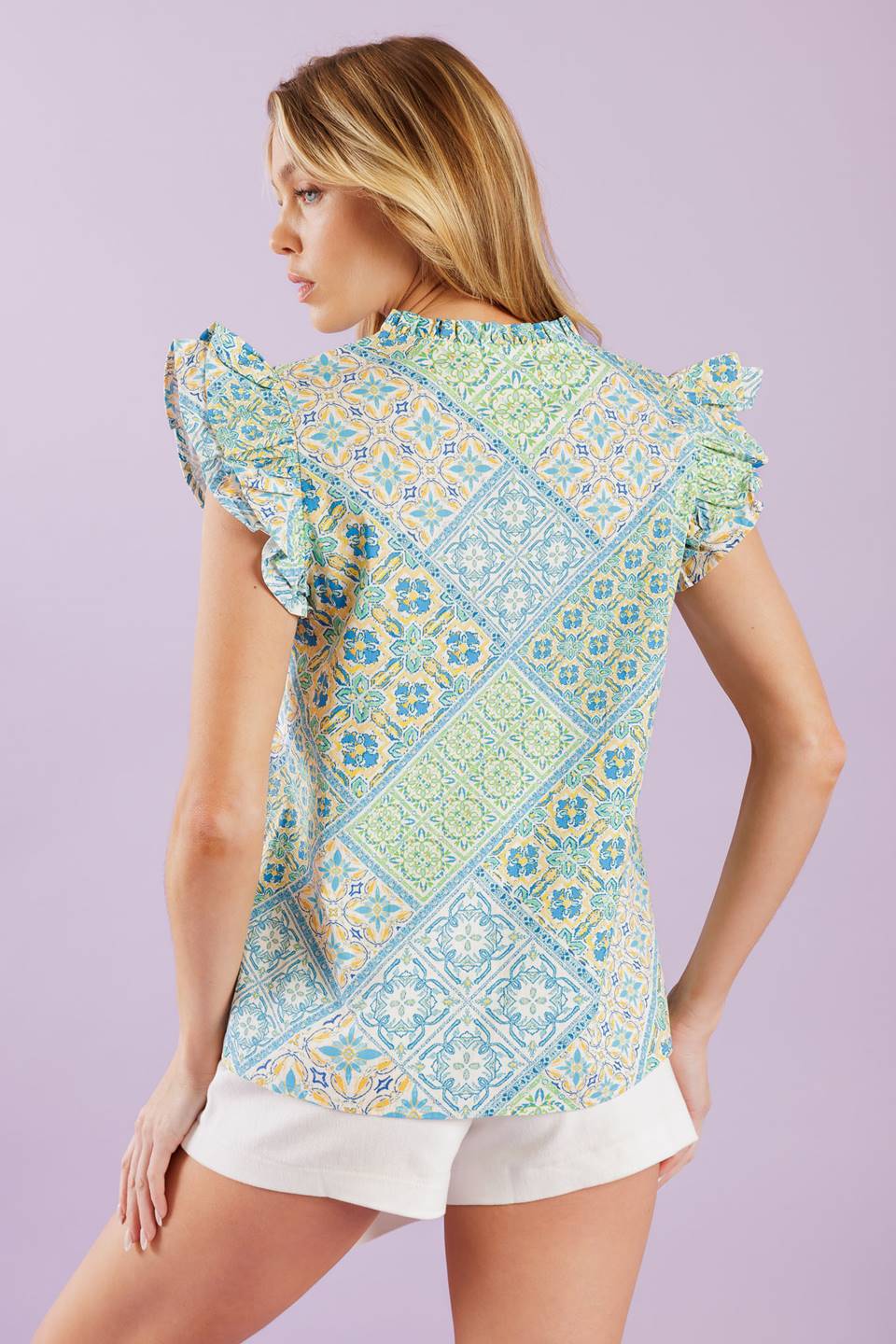 A printed woven top featuring ruffled neckline with V front and ruffled sleeve