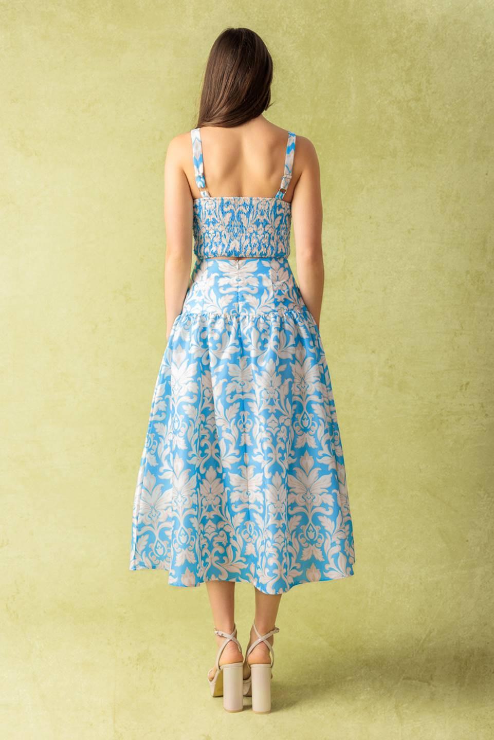 A printed woven top and skirt set. Top featuring a straight neckline, shoulder straps, and smocked back bodice. Full skirt with back zipper closure