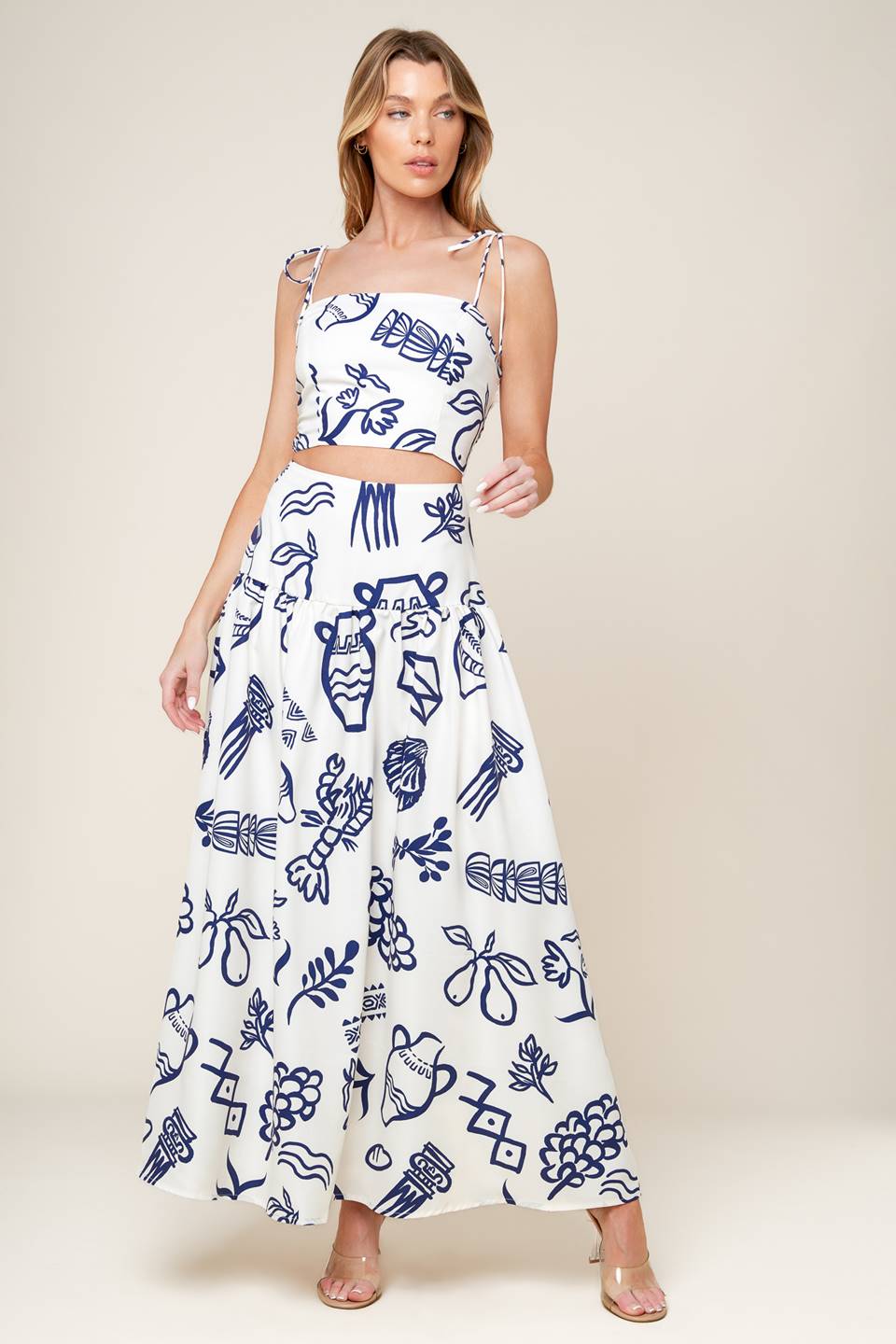 A printed woven top and skirt set. Crop top featuring straight neckline, shoulder tie and smocked back bodice. Full skirt with back zipper closure.