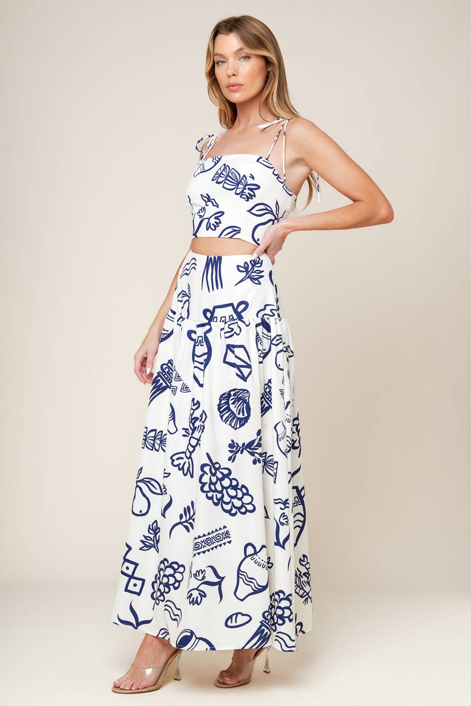 A printed woven top and skirt set. Crop top featuring straight neckline, shoulder tie and smocked back bodice. Full skirt with back zipper closure.