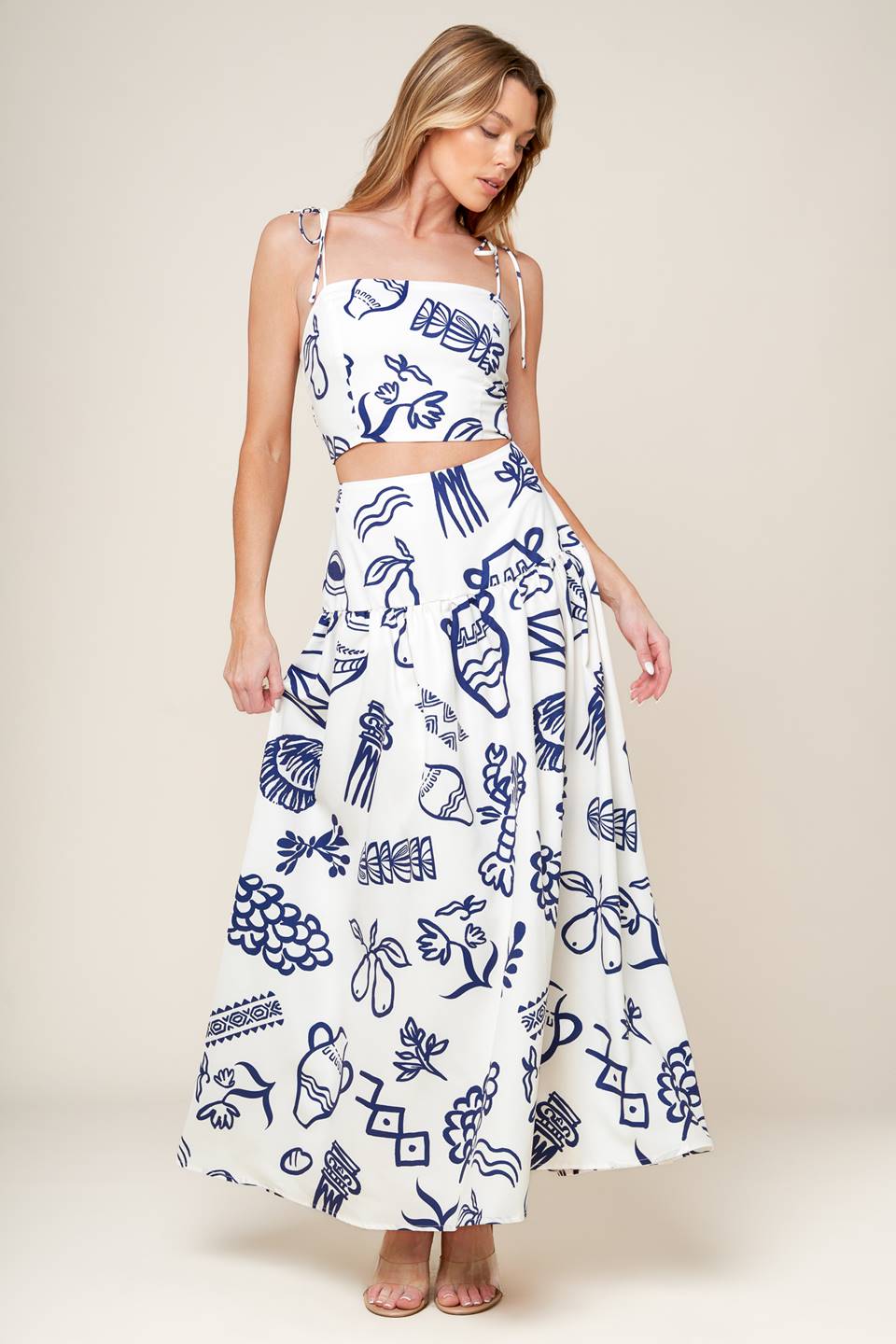 A printed woven top and skirt set. Crop top featuring straight neckline, shoulder tie and smocked back bodice. Full skirt with back zipper closure.