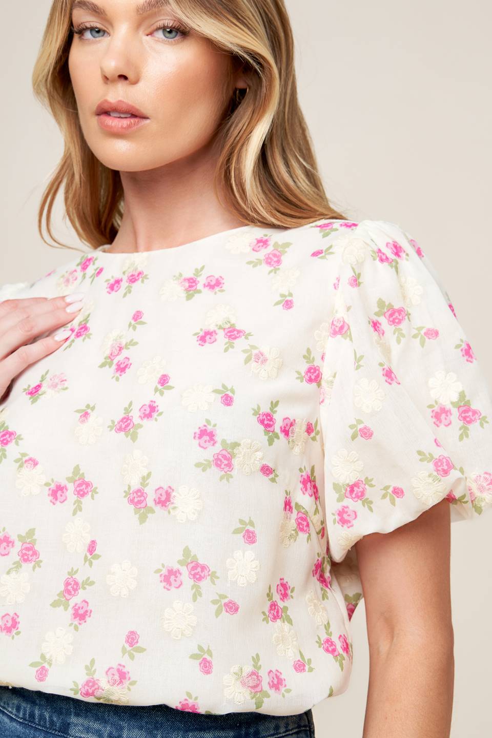 A textured floral printed woven top featuring round neckline, short balloon sleeves and back neck tie closure.