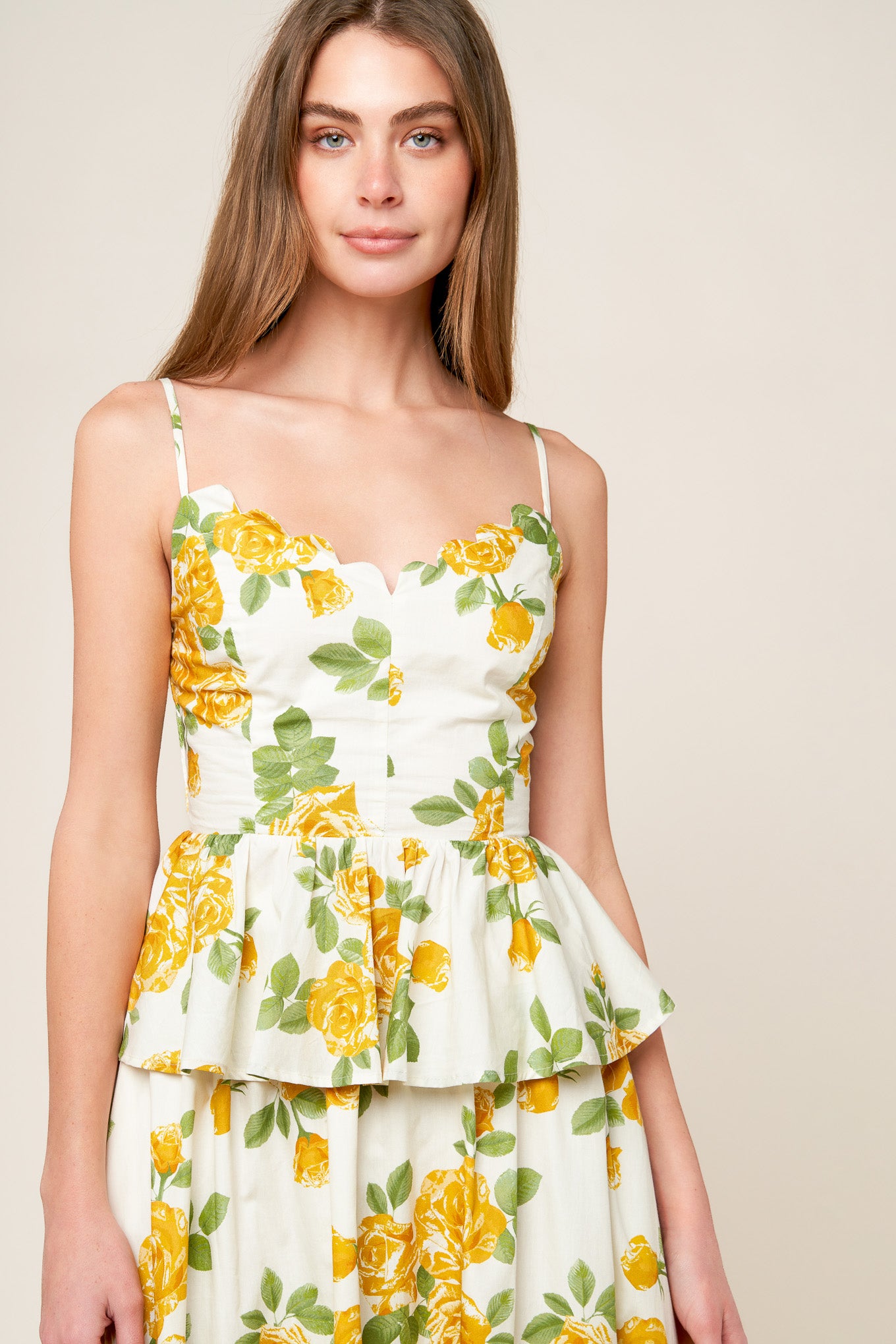 A printed woven top featuring scalloped V neckline, straps, peplum, full skirt and smocked back bodice