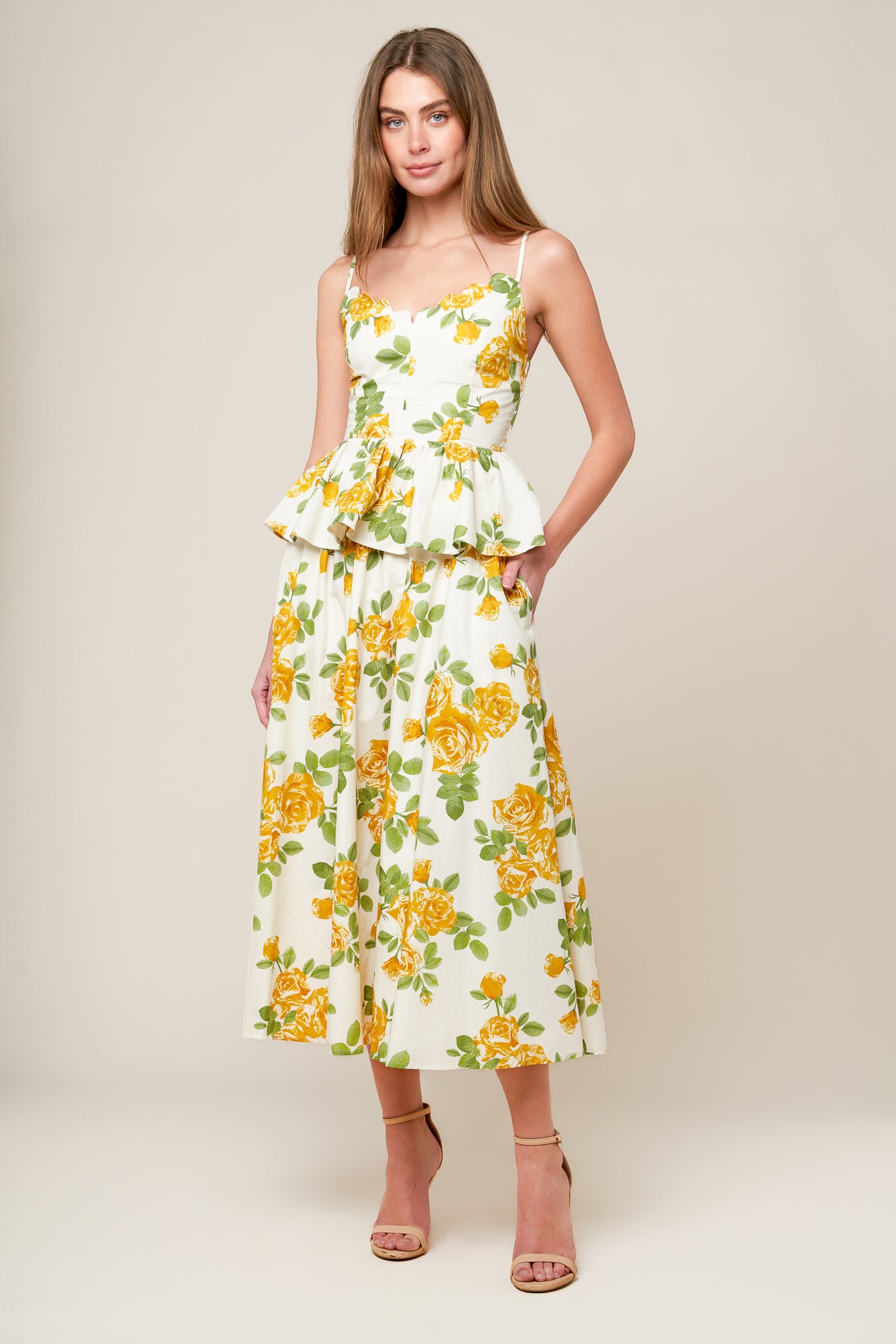 A printed woven top featuring scalloped V neckline, straps, peplum, full skirt and smocked back bodice