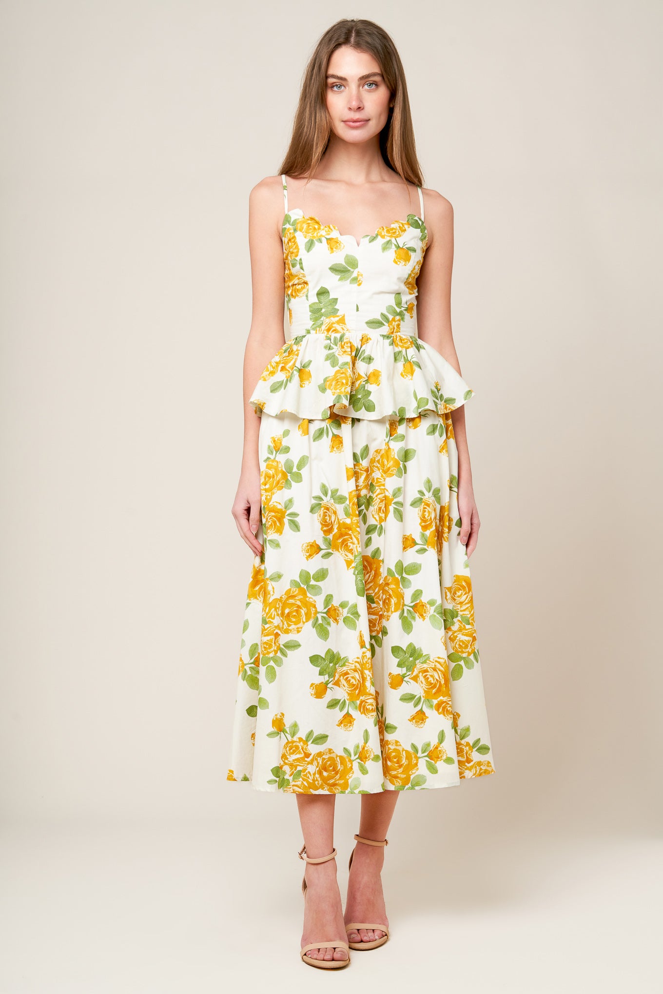 A printed woven top featuring scalloped V neckline, straps, peplum, full skirt and smocked back bodice