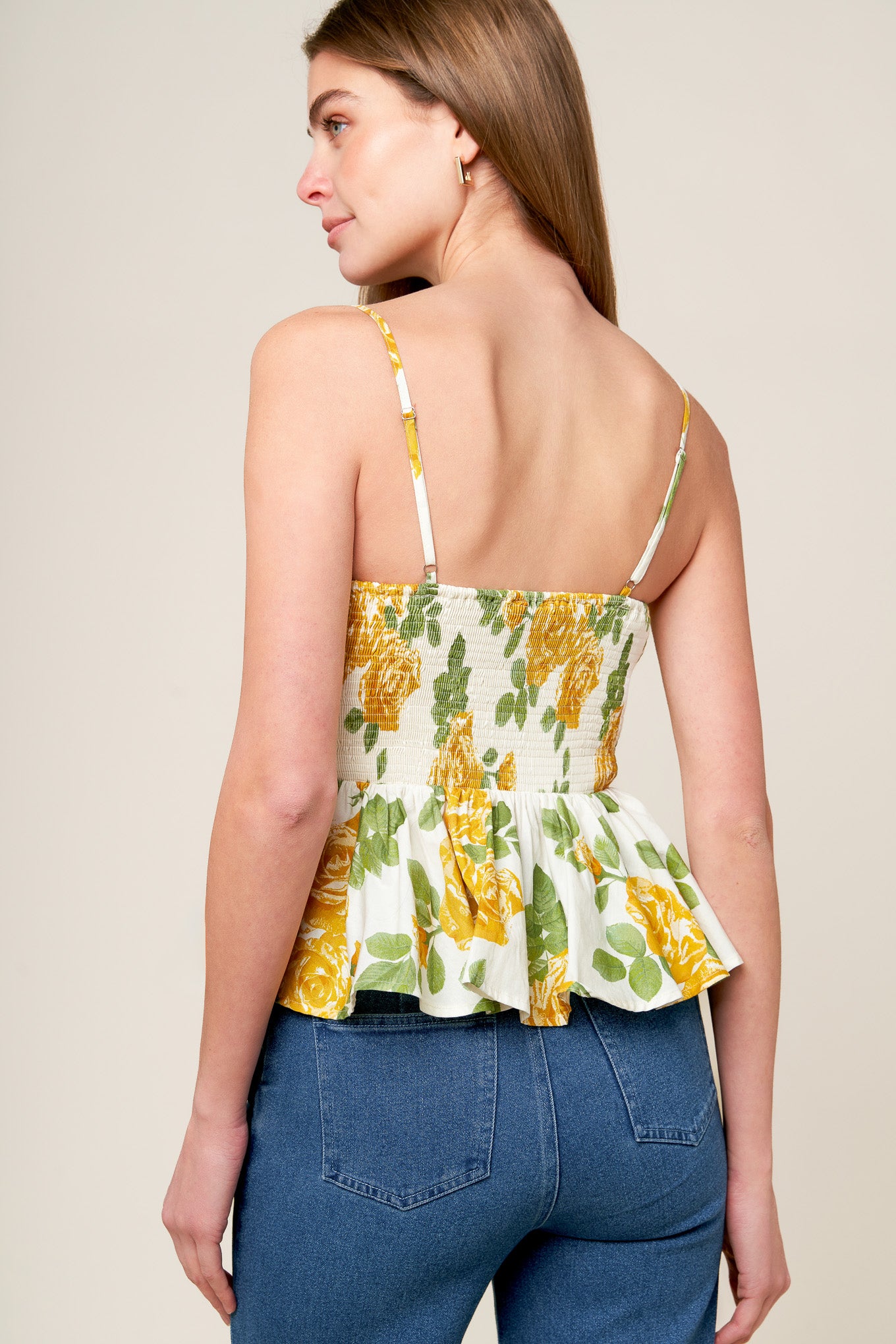 A printed woven top featuring scalloped V neckline, straps, peplum, full skirt and smocked back bodice