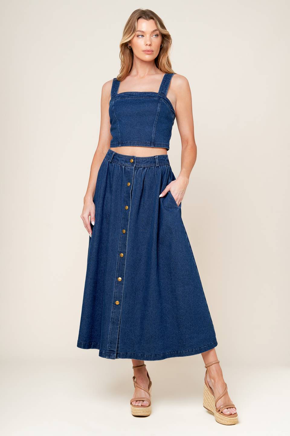 A washed denim top and skirt set. Top featuring cropped length, straight neckline, strap and back zipper closure. Skirt featuring full skirt with front button closure.