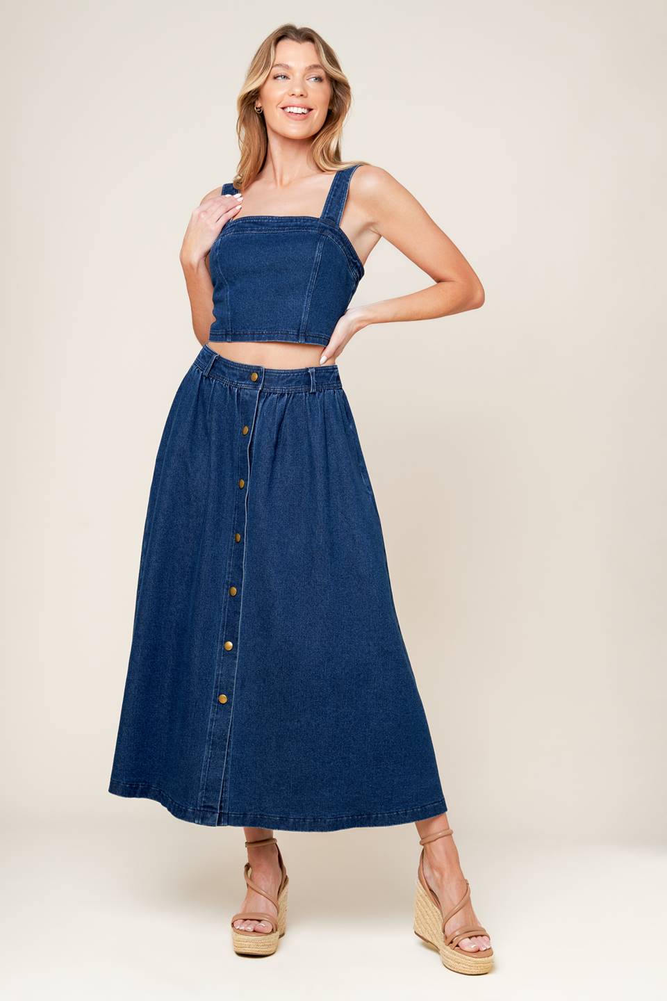 A washed denim top and skirt set. Top featuring cropped length, straight neckline, strap and back zipper closure. Skirt featuring full skirt with front button closure.