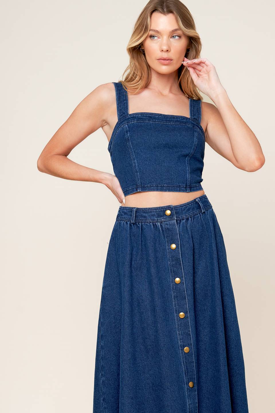 A washed denim top and skirt set. Top featuring cropped length, straight neckline, strap and back zipper closure. Skirt featuring full skirt with front button closure.