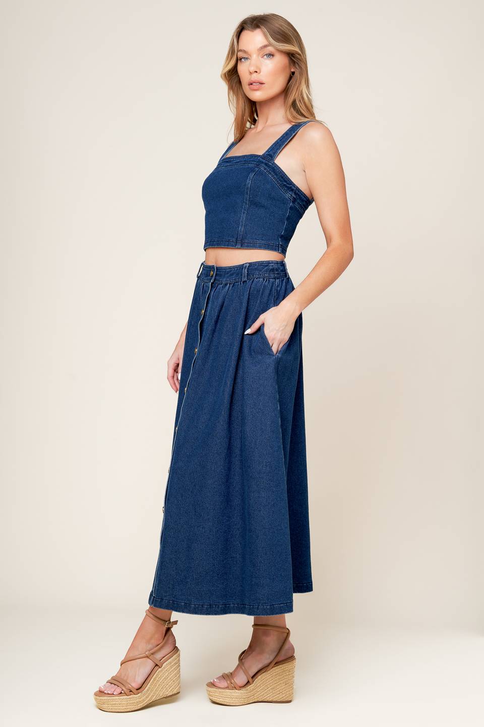 A washed denim top and skirt set. Top featuring cropped length, straight neckline, strap and back zipper closure. Skirt featuring full skirt with front button closure.