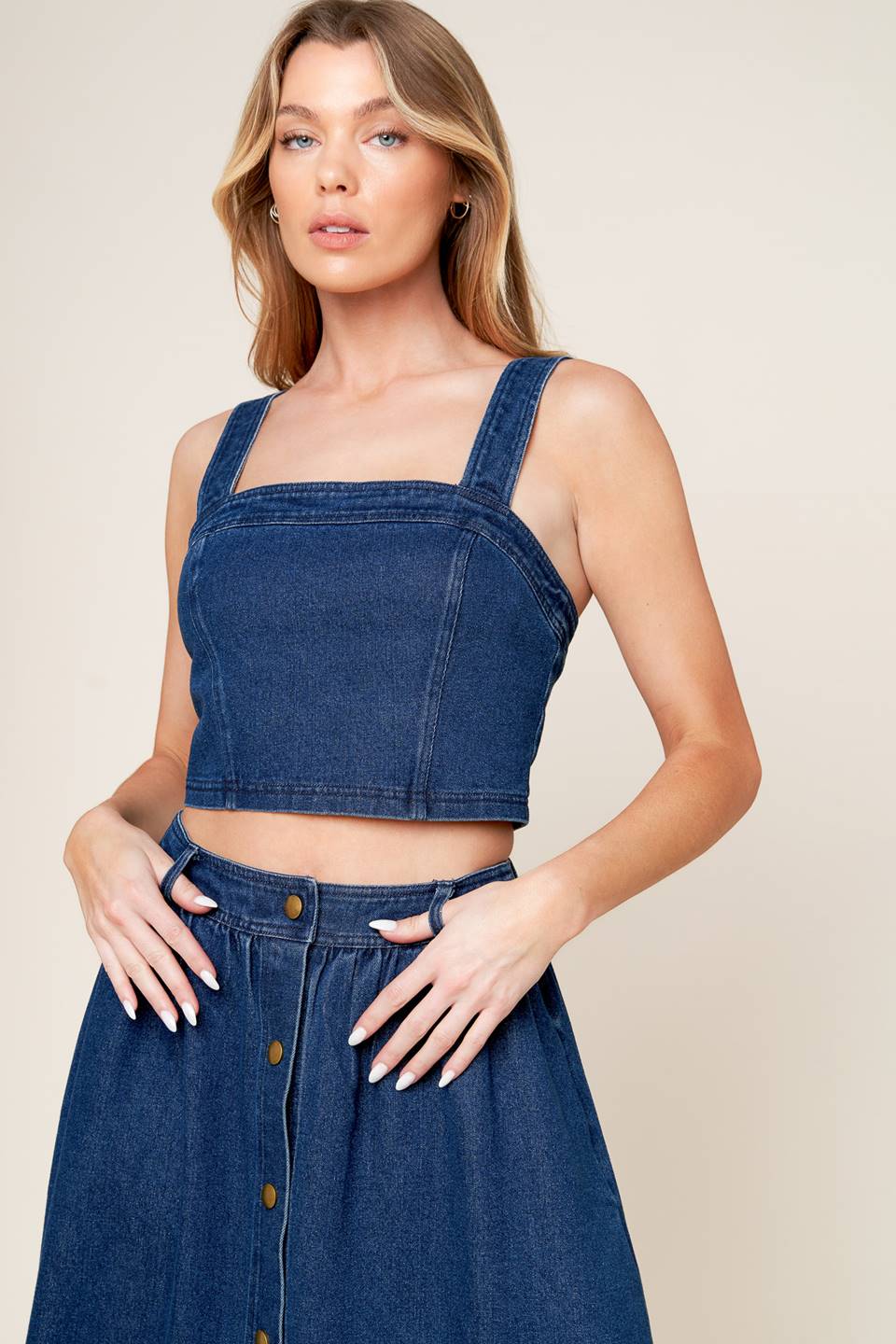 A washed denim top and skirt set. Top featuring cropped length, straight neckline, strap and back zipper closure. Skirt featuring full skirt with front button closure.