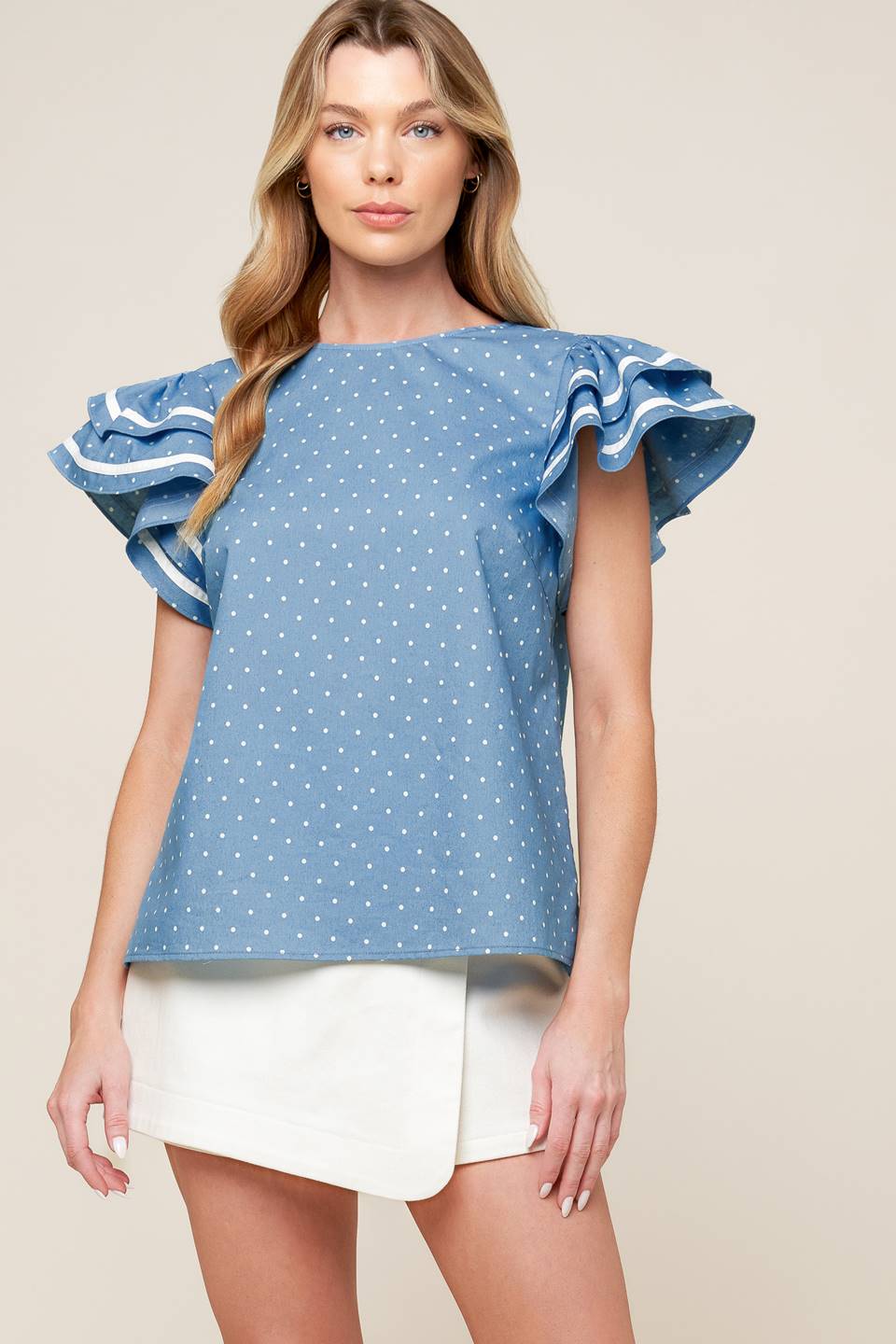 A printed woven top featuring round neckline, double ruffled sleeves and back neck button closure.