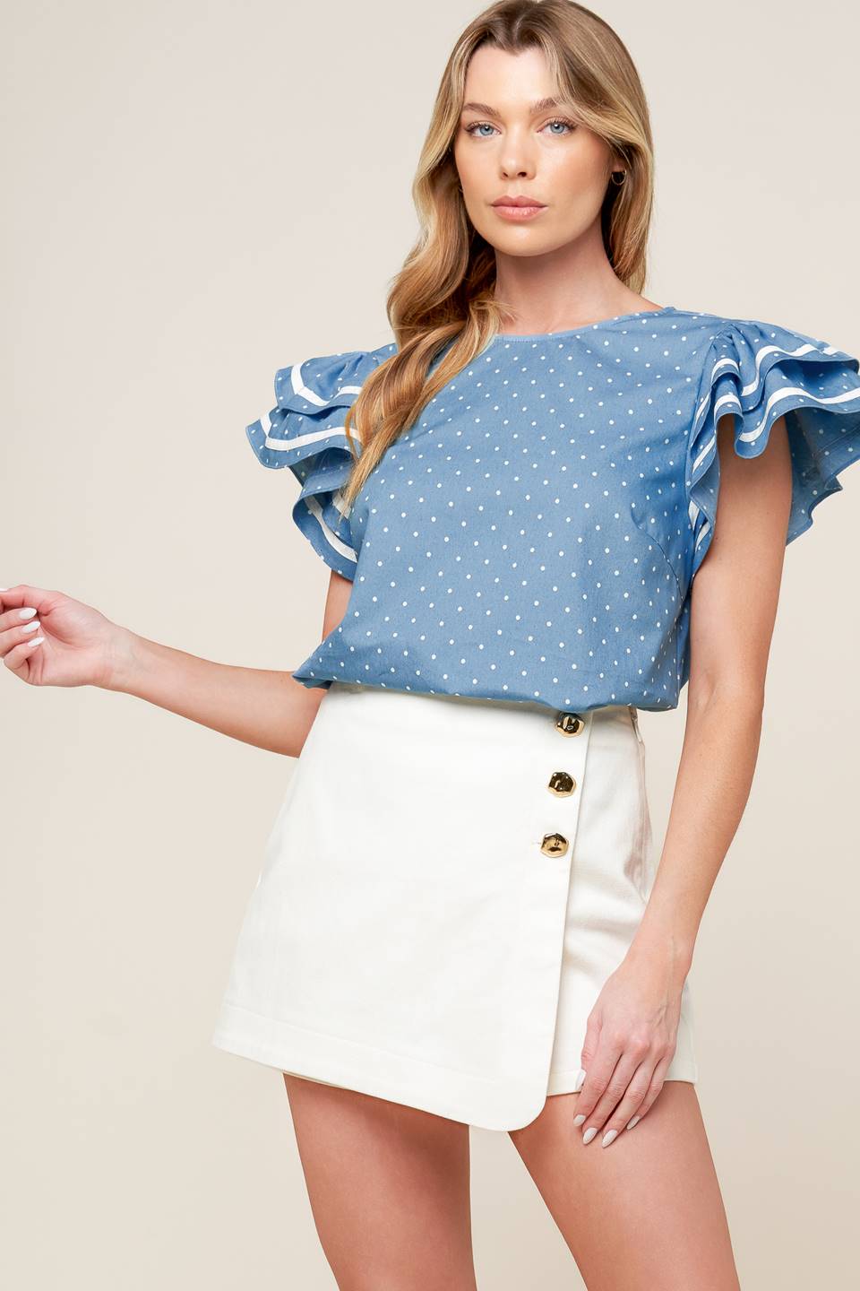 A printed woven top featuring round neckline, double ruffled sleeves and back neck button closure.