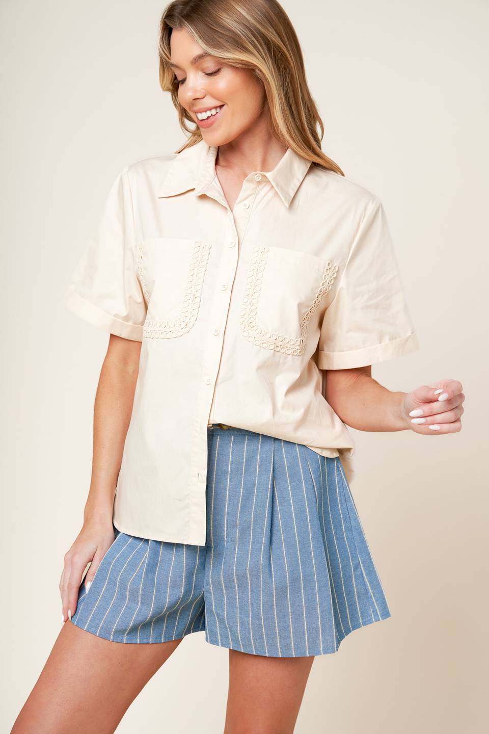 A soild woven top featuring button down, cuffed short sleeve and lace trimmed pockets.