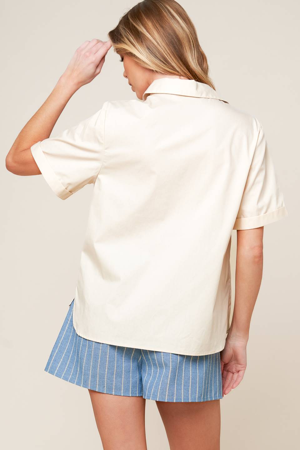 A soild woven top featuring button down, cuffed short sleeve and lace trimmed pockets.