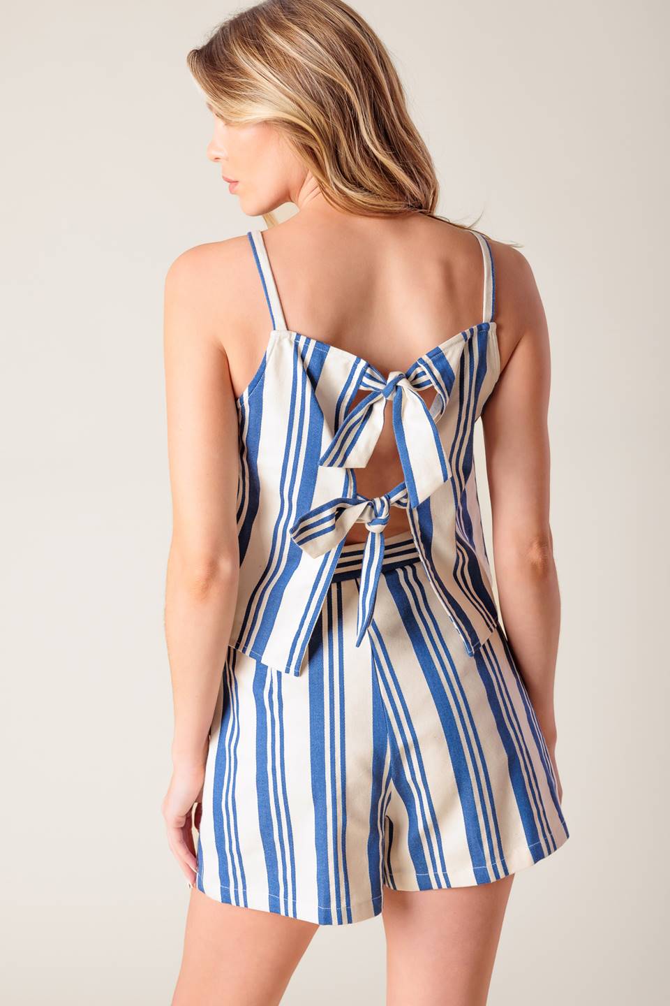 A blue and ivory striped printed woven top and short set. Top featuring round neckline, sleeveless and back tie. Short with side zipper closure.