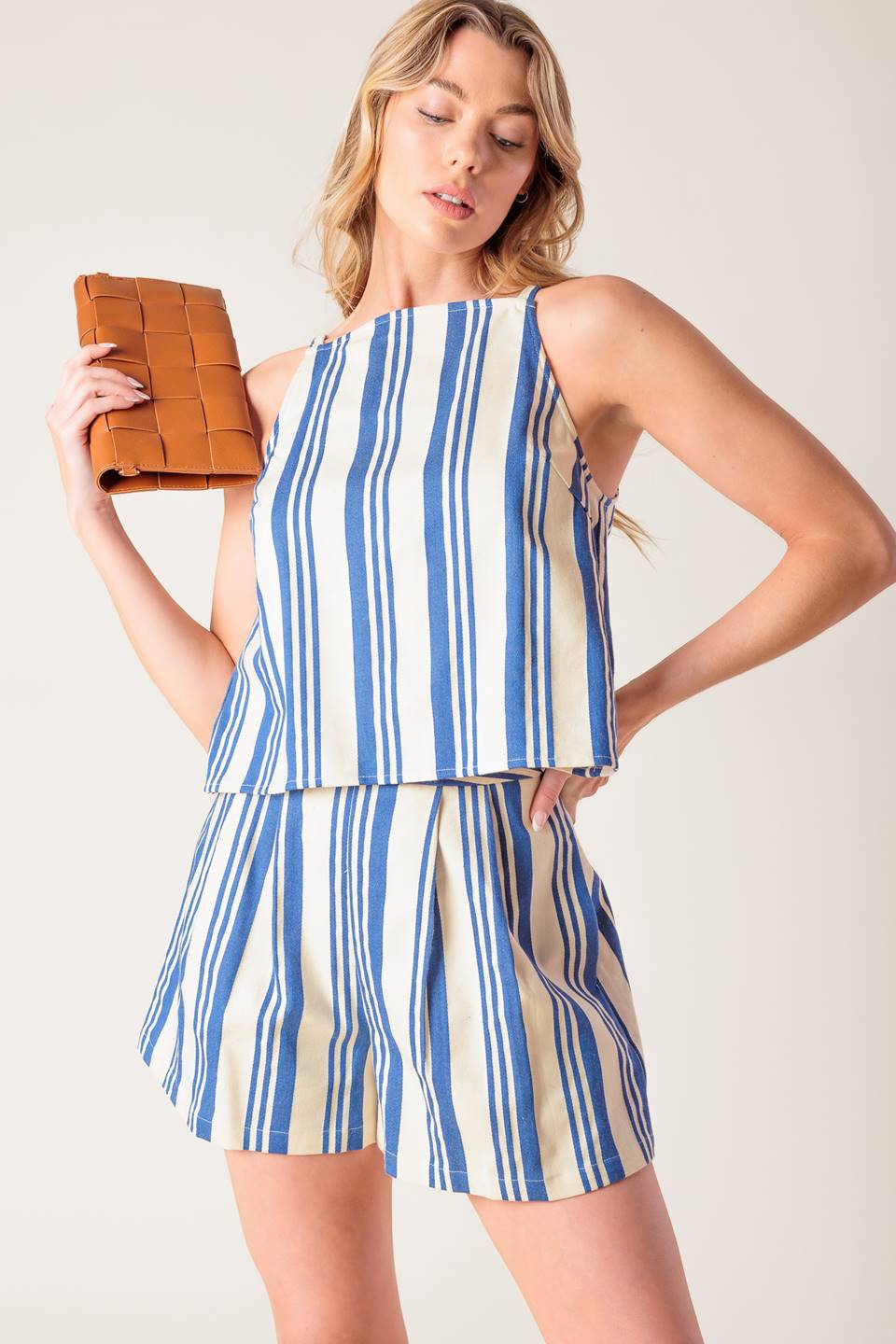 A blue and ivory striped printed woven top and short set. Top featuring round neckline, sleeveless and back tie. Short with side zipper closure.