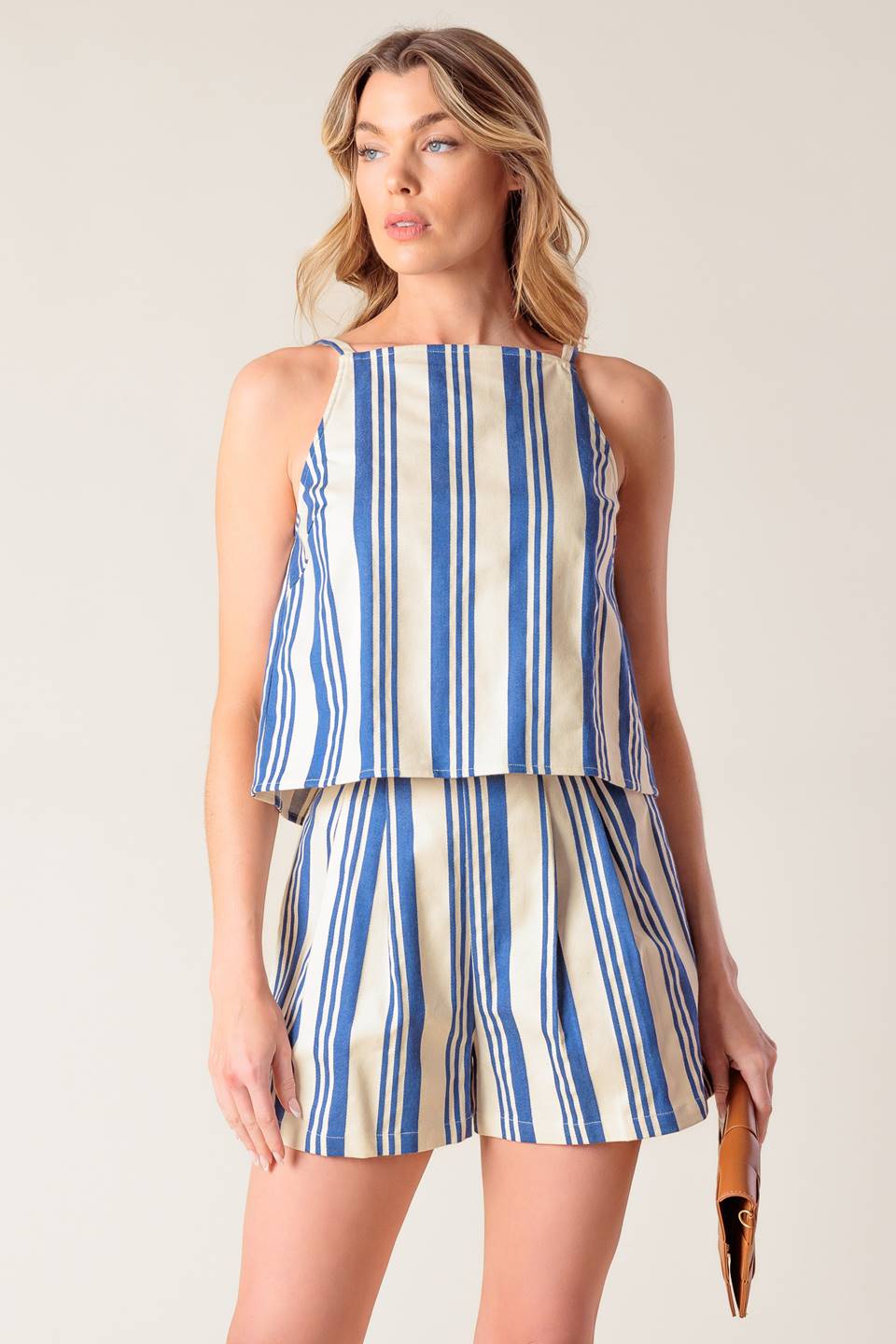 A blue and ivory striped printed woven top and short set. Top featuring round neckline, sleeveless and back tie. Short with side zipper closure.