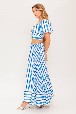 A striped woven top and skirt set. Top featuring sweetheart neckline with center bow and cut out, short puff sleeve and smocked back bodice. Circle skirt featuring side tie and zipper closure
