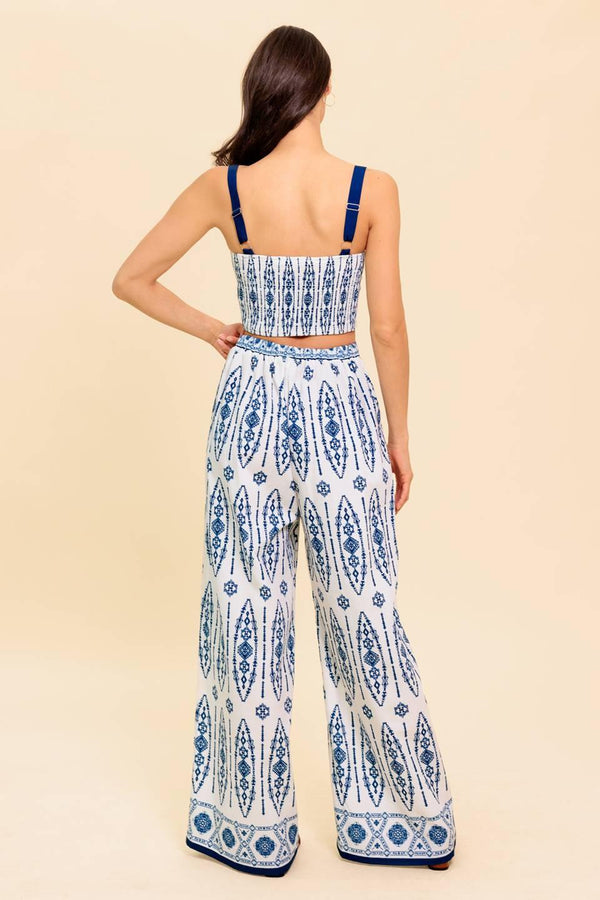 A printed woven top and pant set. Crop top featuring straight neckline, straps and smocked back bodice. Pant featuring wide leg and side zipper closure