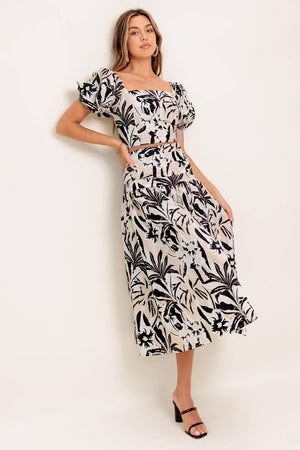 A printed woven top and skirt set featuring square neckline crop top with short puff sleeve and smocked back bodice. Matching skirt with side zipper closure