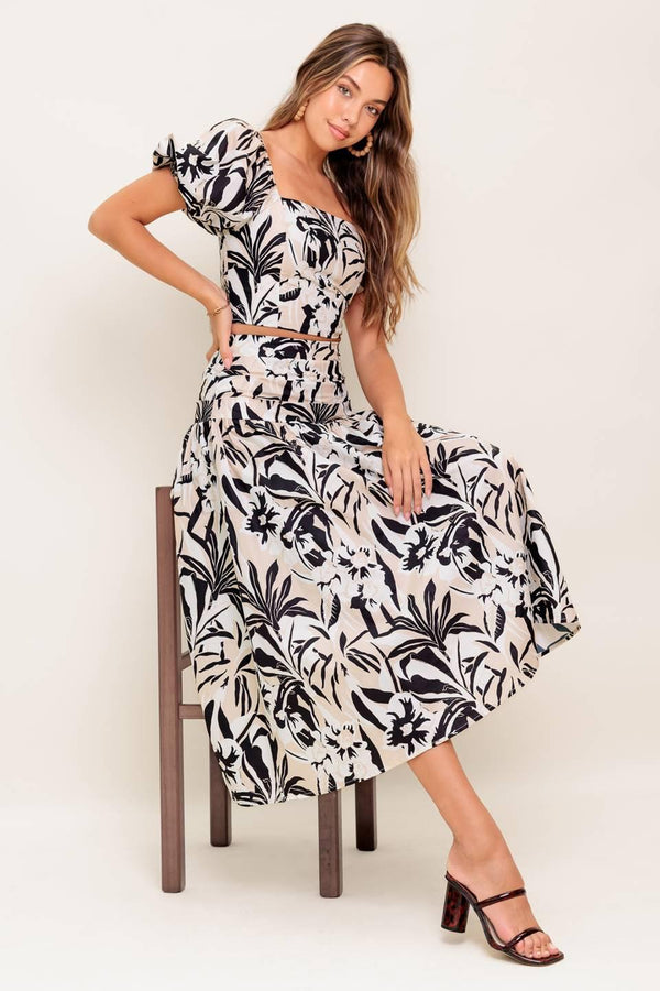A printed woven top and skirt set featuring square neckline crop top with short puff sleeve and smocked back bodice. Matching skirt with side zipper closure