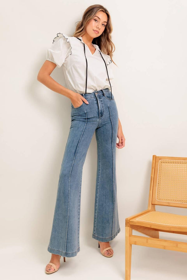A solid woven top featuring ruffed neckline with tie, scallop edge shoulder and short sleeve