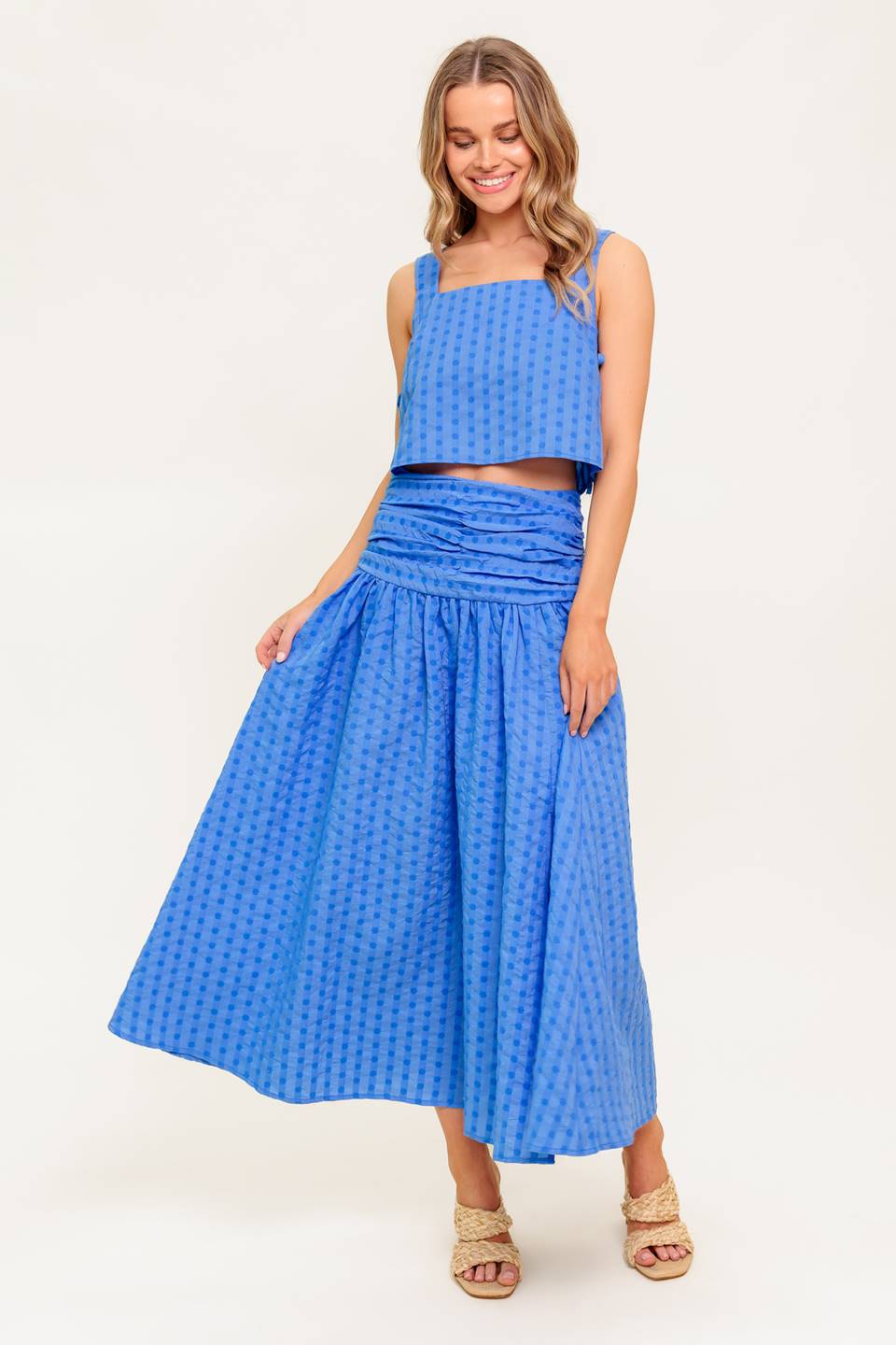 A textured woven top and skirt set. Top featuring square neckline, sleeveless, side, and side. Skirt featuring shirred waistband, full skirt, and back zipper closure.