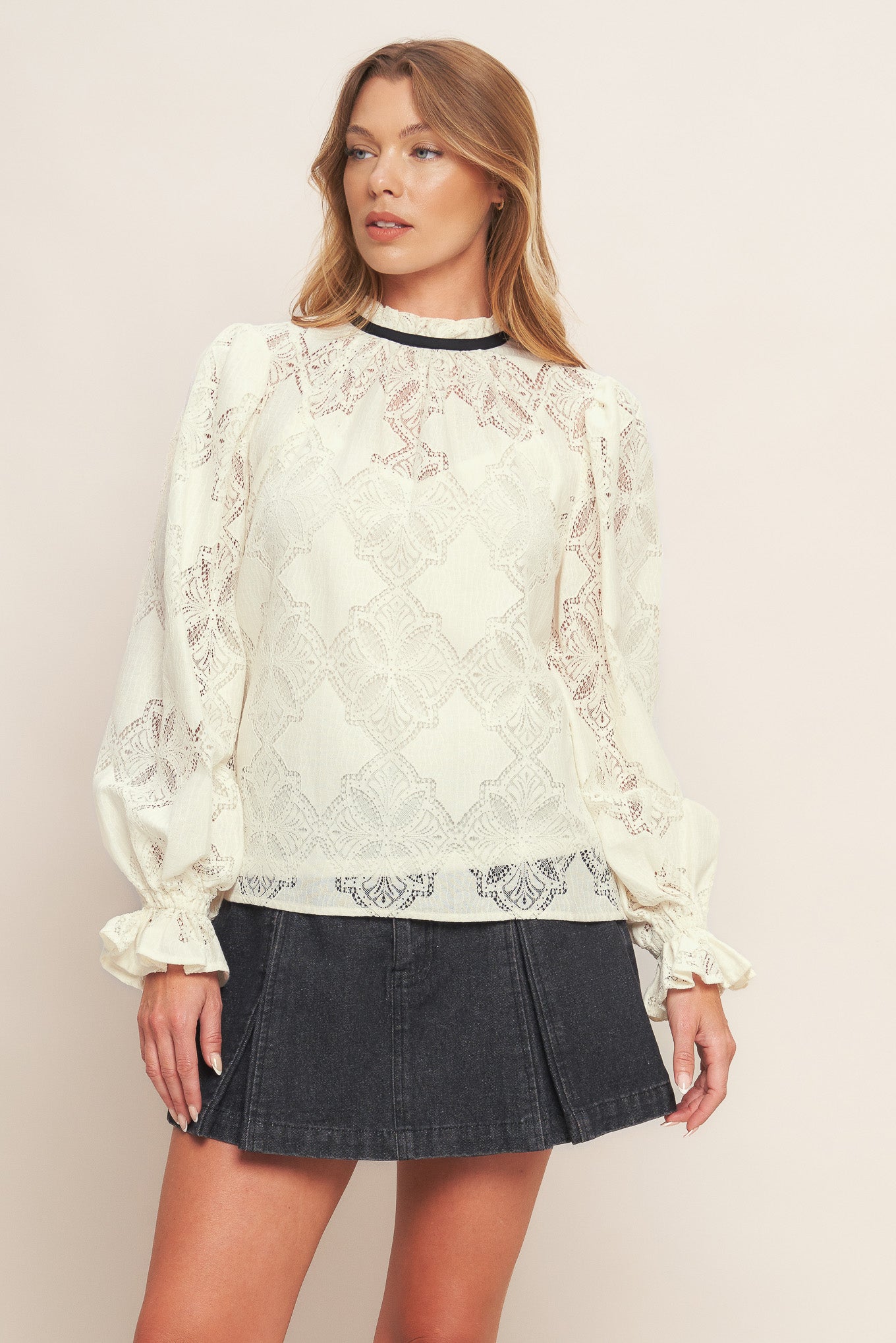 A woven lace top featuring ruffled high neckline with contrasting band, long sleeve with ruffled cuff, cami and back neck tie closure
