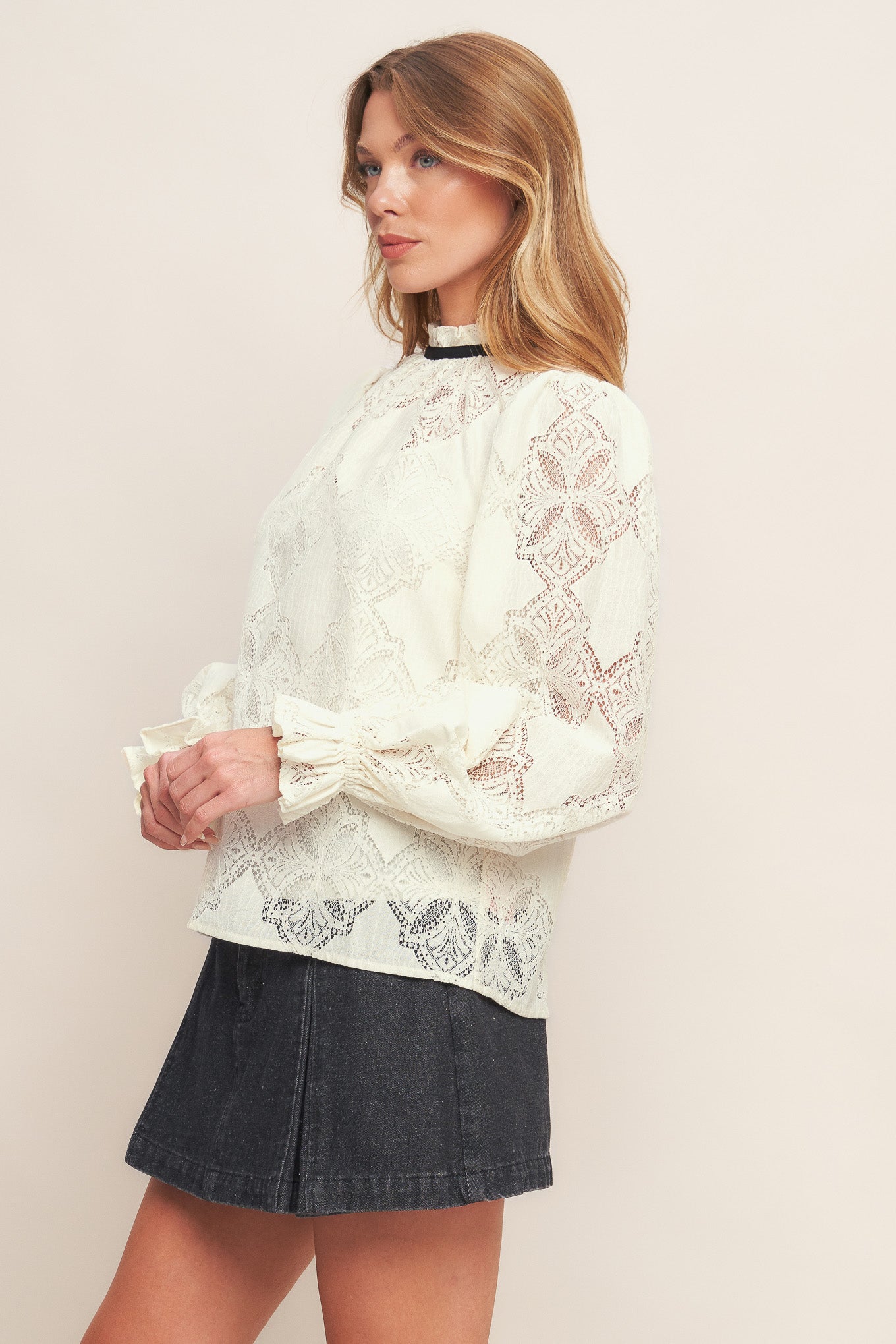 A woven lace top featuring ruffled high neckline with contrasting band, long sleeve with ruffled cuff, cami and back neck tie closure

