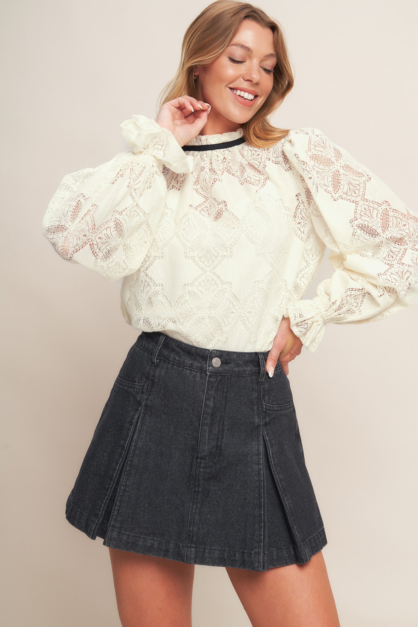 A woven lace top featuring ruffled high neckline with contrasting band, long sleeve with ruffled cuff, cami and back neck tie closure