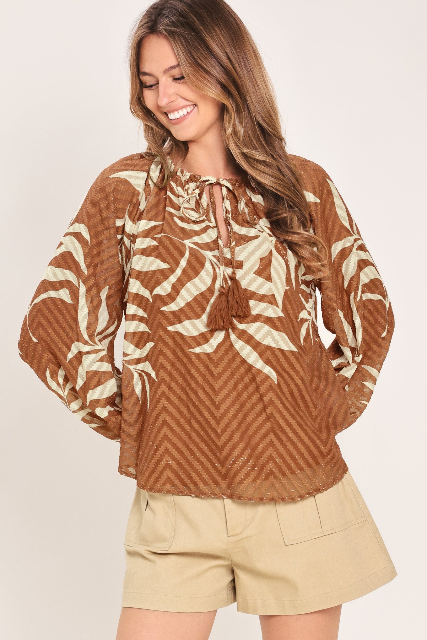 Woman wearing a long sleeve brown and beige leaf patterned blouse | Flying Tomato