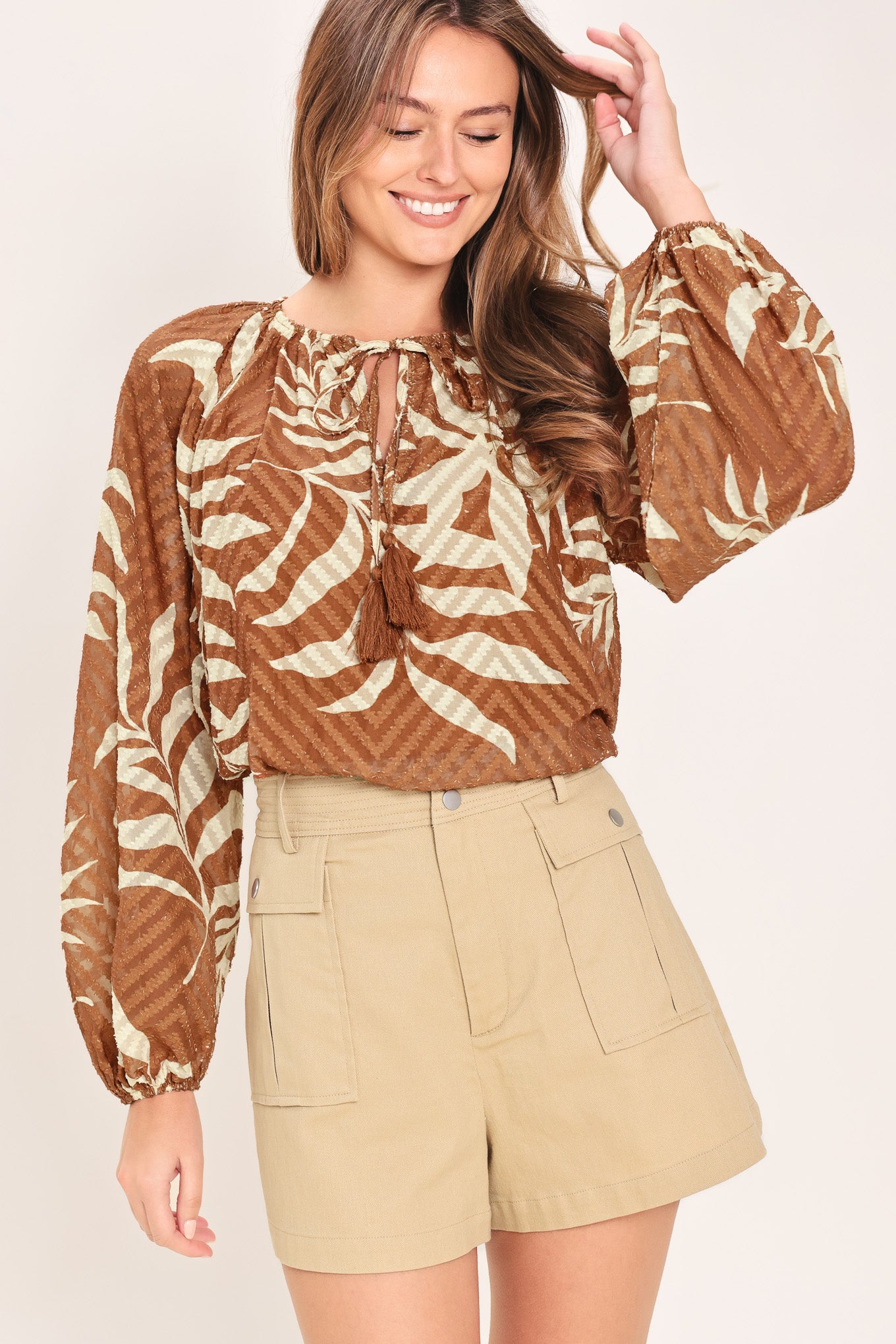 Woman wearing a long sleeve brown and beige leaf patterned blouse | Flying Tomato