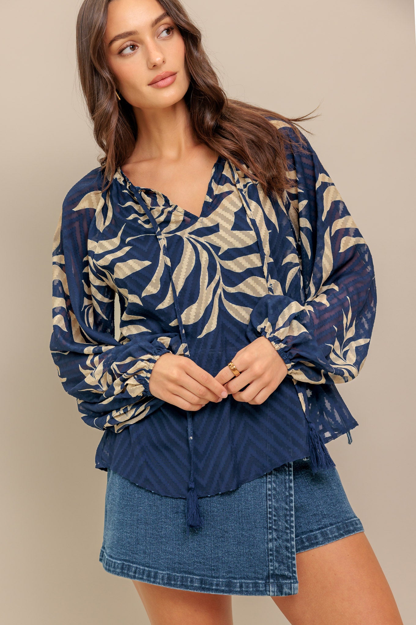 A textured woven top featuring round neckline with tie and long sleeve