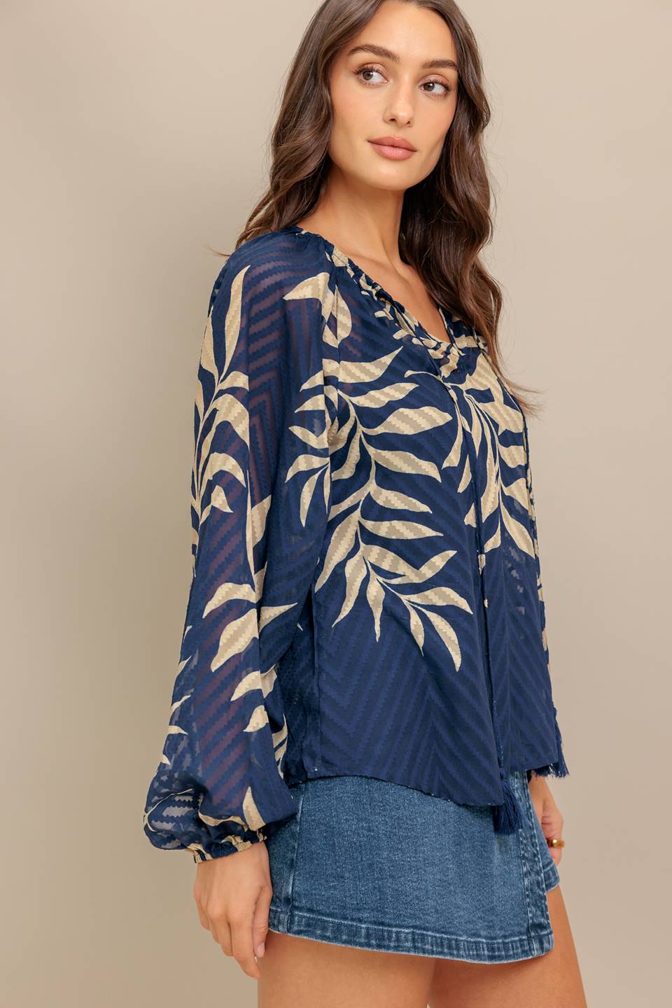 Woman wearing a long sleeve navy blue and beige leaf patterned blouse | Flying Tomato