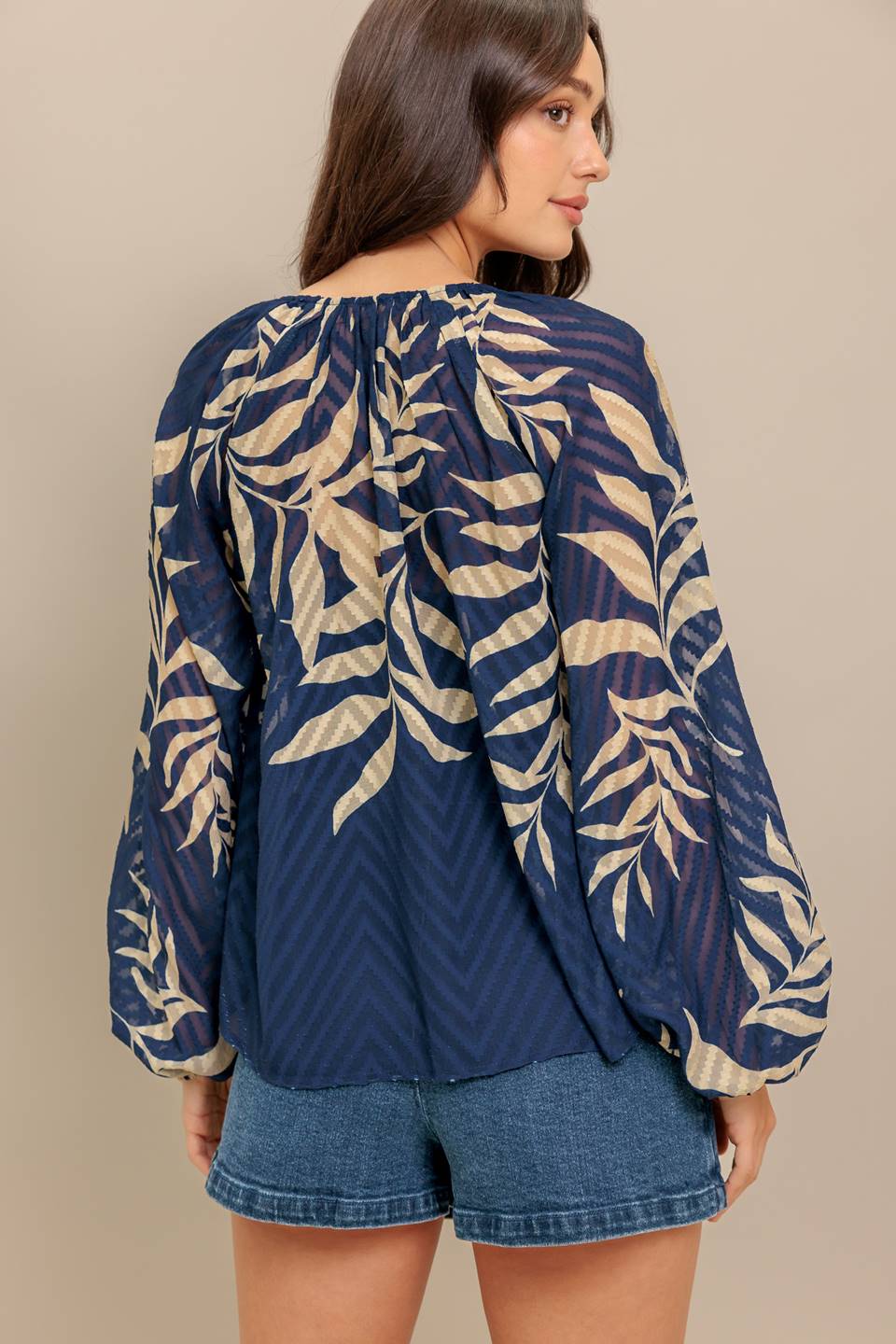Woman wearing a long sleeve navy blue and beige leaf patterned blouse | Flying Tomato
