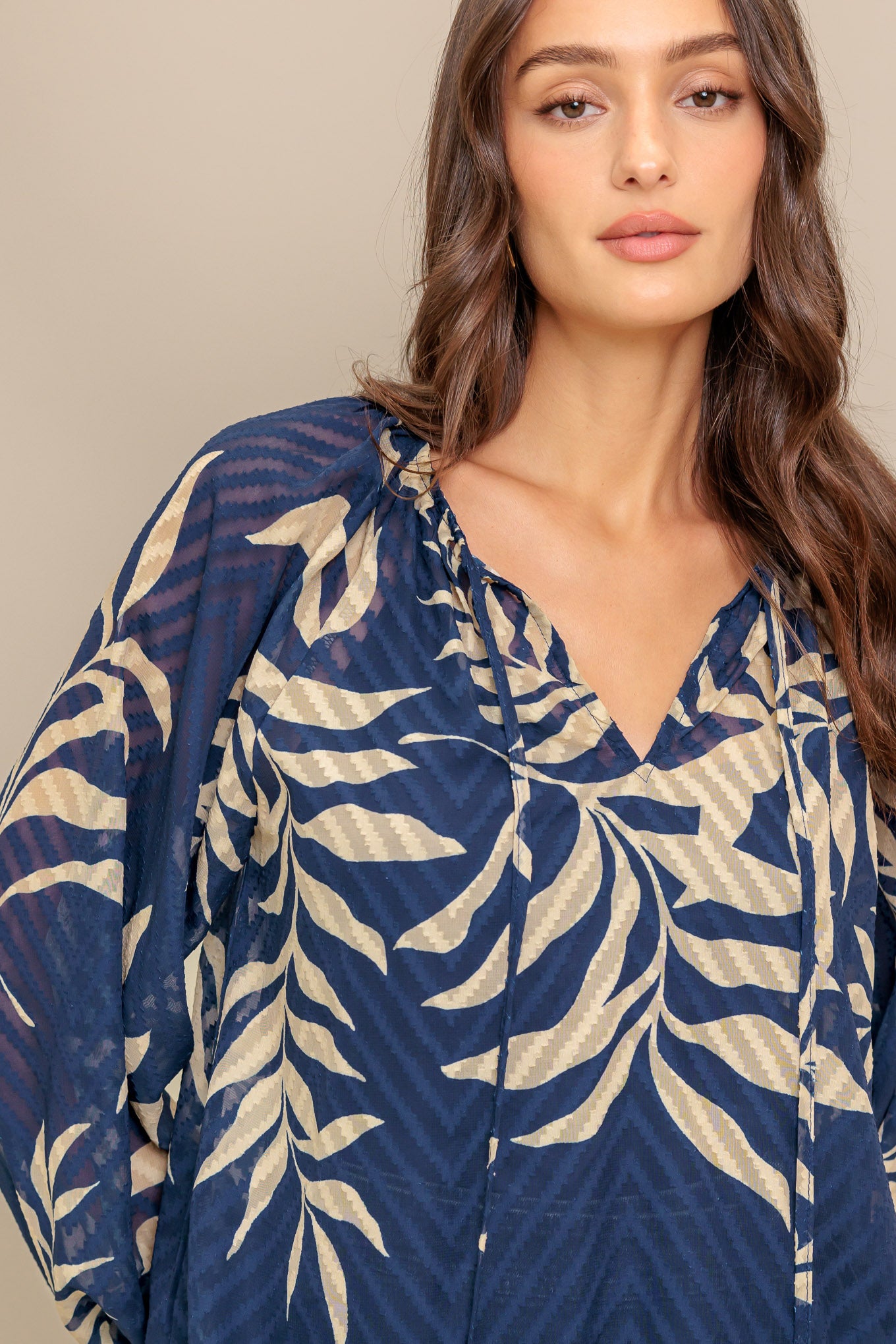 A textured woven top featuring round neckline with tie and long sleeve