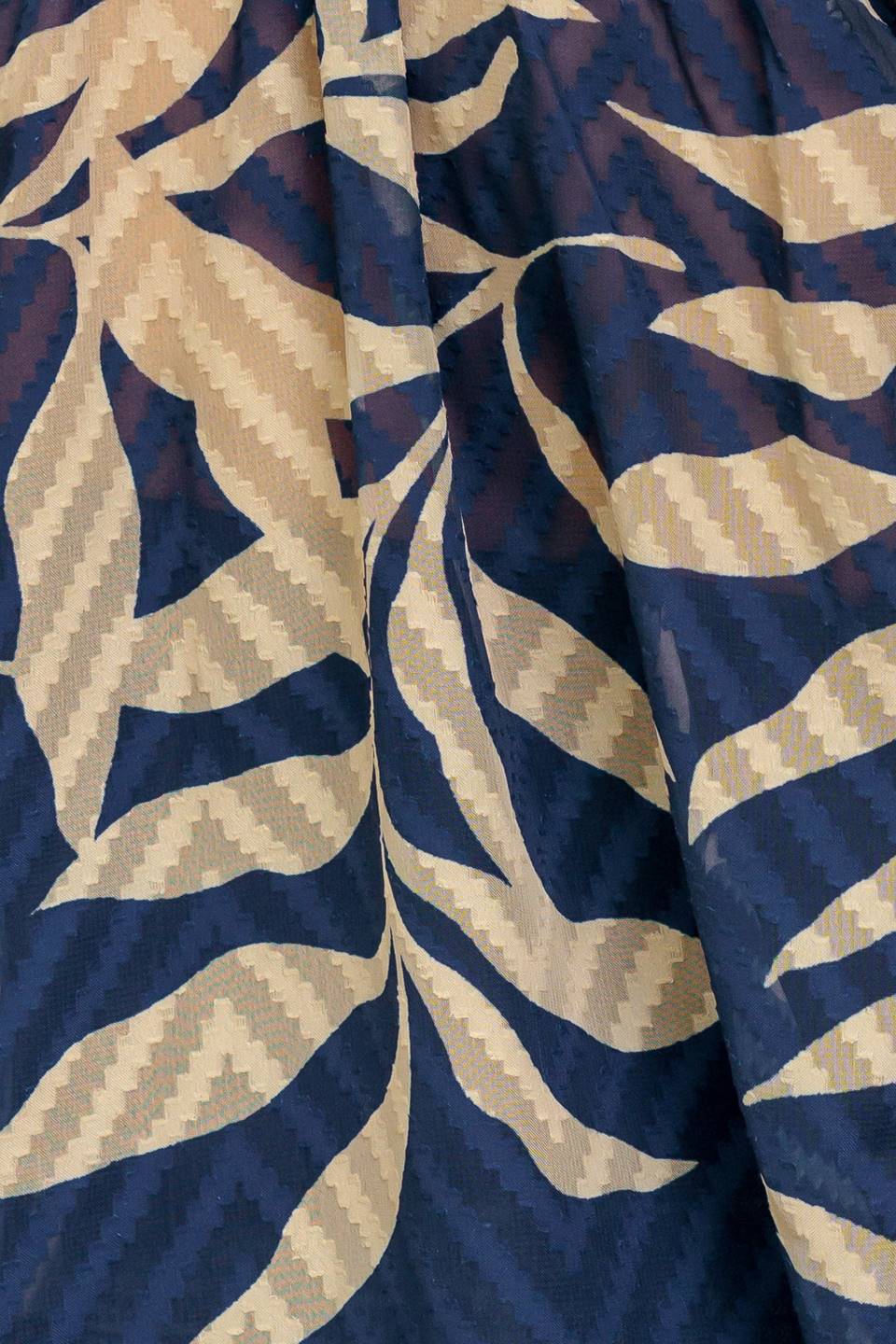 Woman wearing a long sleeve navy blue and beige leaf patterned blouse | Flying Tomato