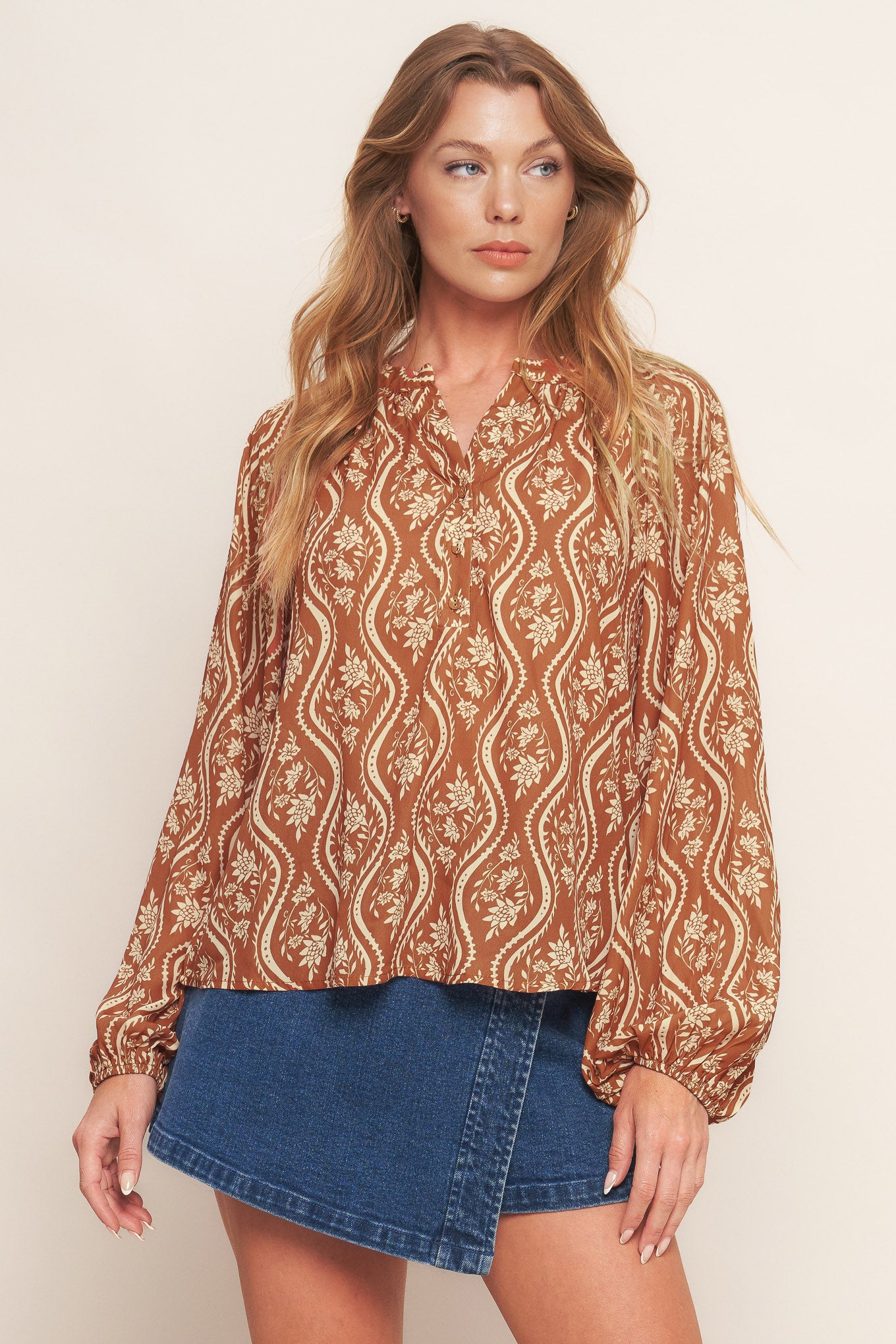A printed woven top featuring round neckline with V front and long raglan sleeve