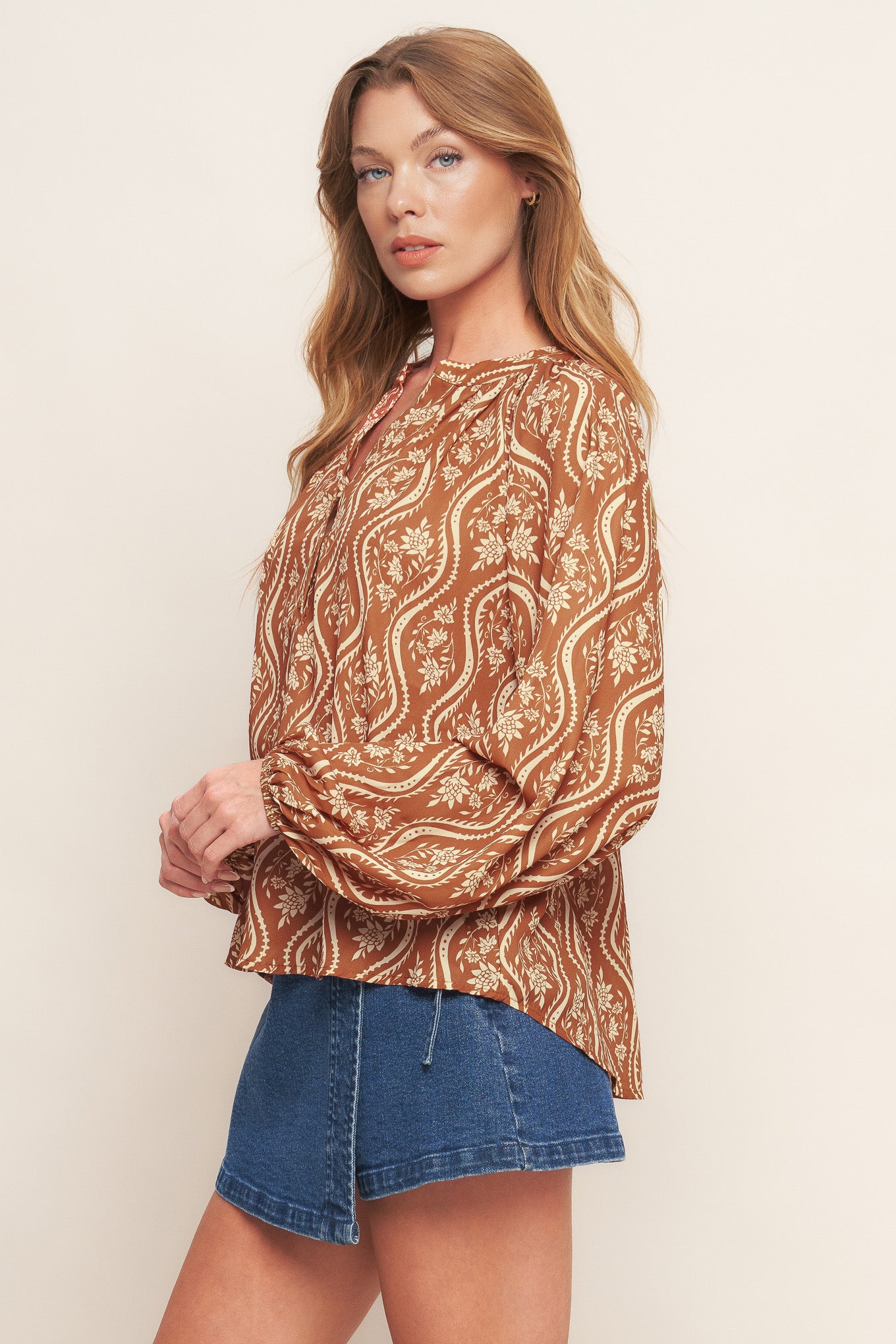 A printed woven top featuring round neckline with V front and long raglan sleeve