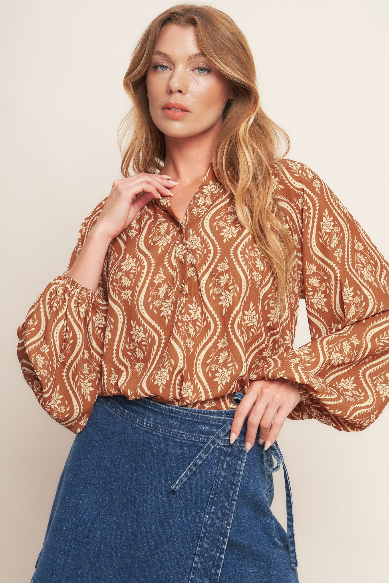 A printed woven top featuring round neckline with V front and long raglan sleeve