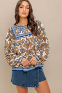 A printed woven top featuring round neckline, yoke, long sleeve and back neck button closure