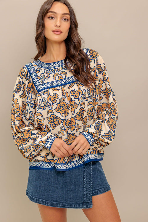A printed woven top featuring round neckline, yoke, long sleeve and back neck button closure