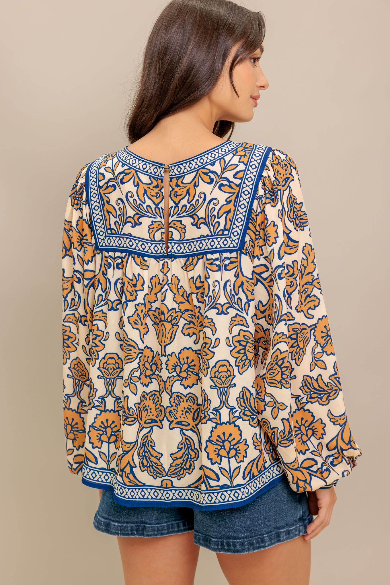 A printed woven top featuring round neckline, yoke, long sleeve and back neck button closure