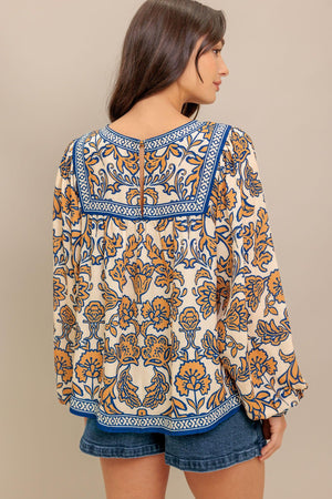 A printed woven top featuring round neckline, yoke, long sleeve and back neck button closure