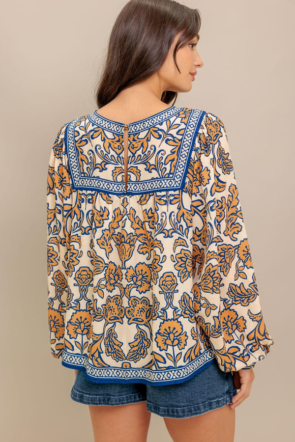 A printed woven top featuring round neckline, yoke, long sleeve and back neck button closure