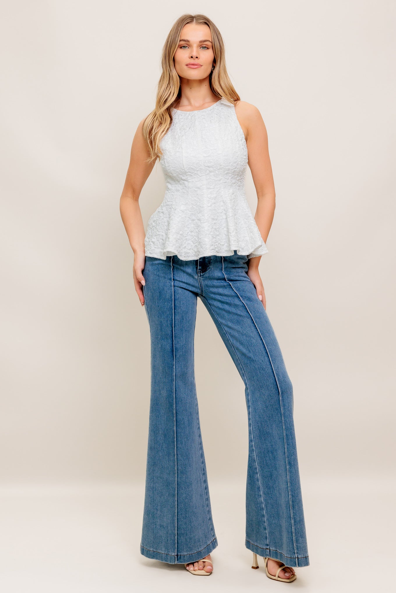 A texture woven top featuring round neckline, bow detail at shoulder, peplum and back zipper closure