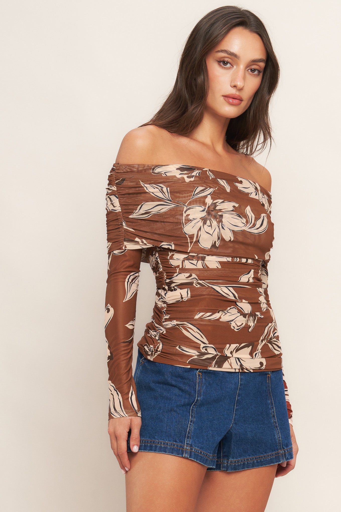 A printed power mesh top featuring off shoulder neckline, long sleeve and side shirring