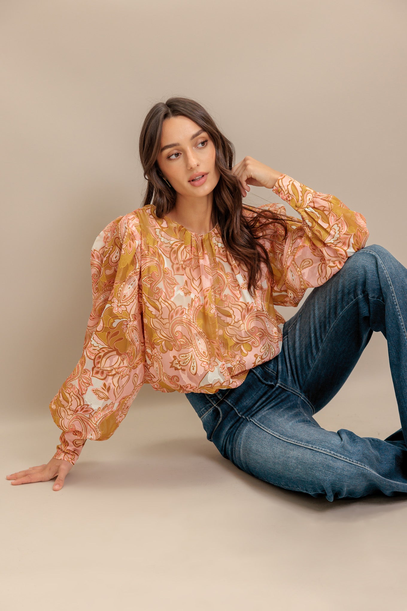 A printed woven jacquard top featuring round neckline, long blouson sleeve with cuff and back neck button closure